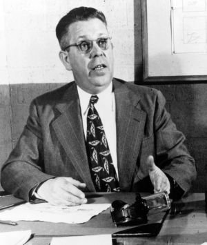 Man in suit speaking at desk