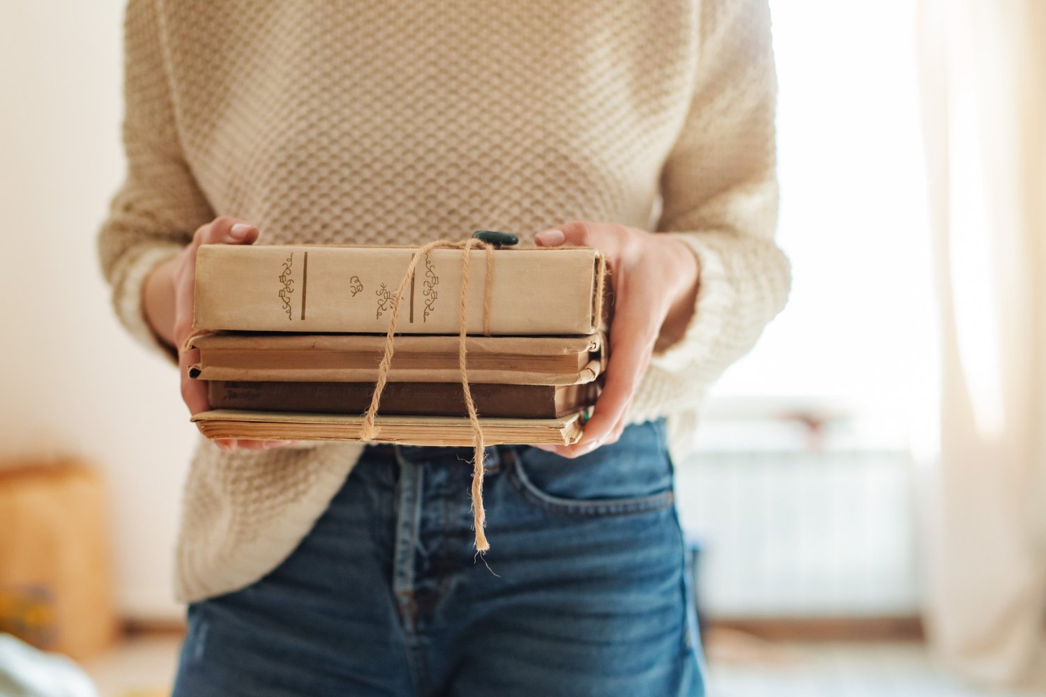 Person holding stack of vintage books tied with twine